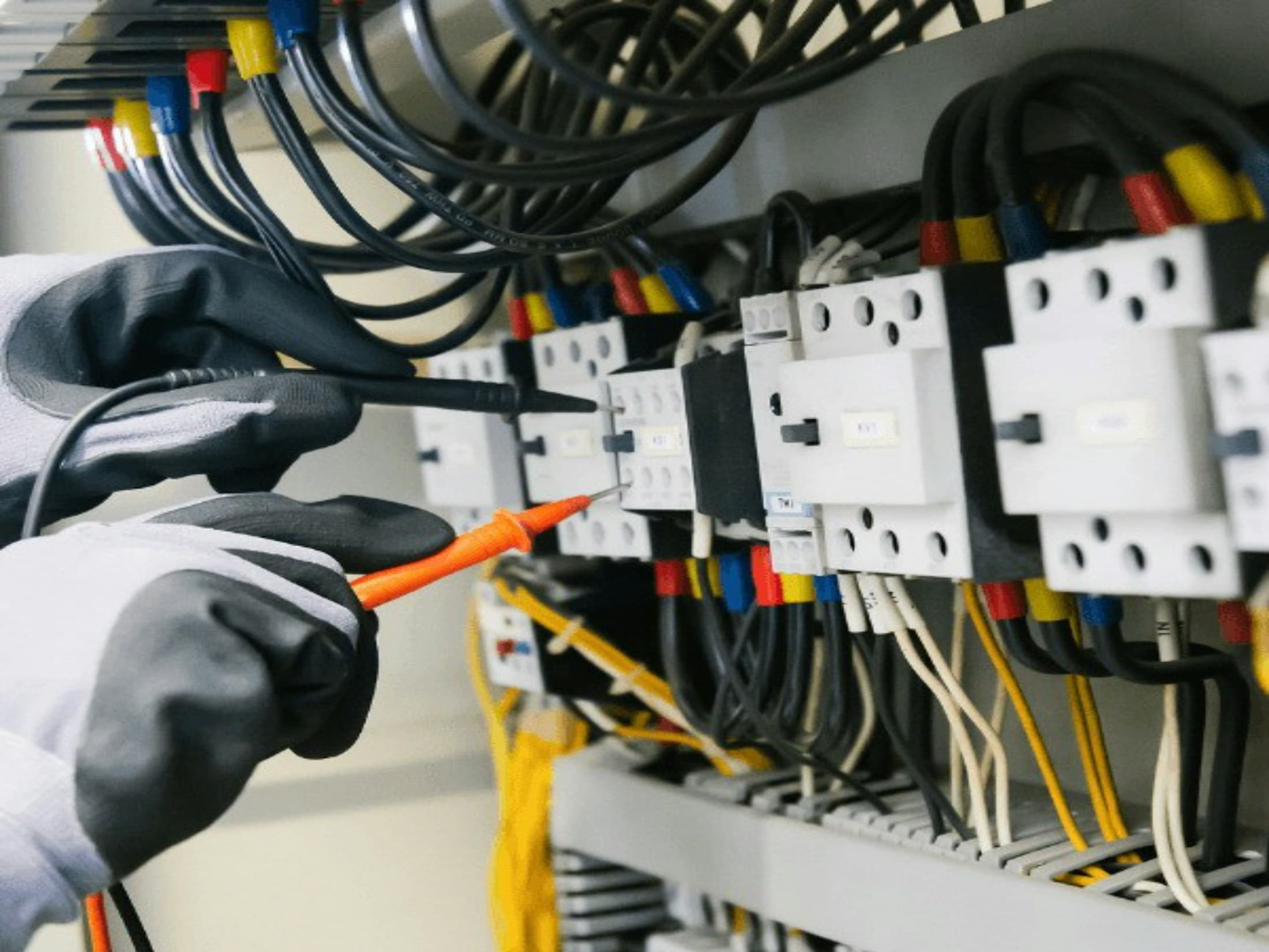 Electrician using test probes inside an electrical control panel